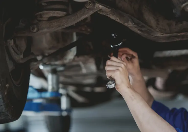 Técnico Midas revisando debajo del auto para confirmar el diagnóstico automotriz en Querétaro